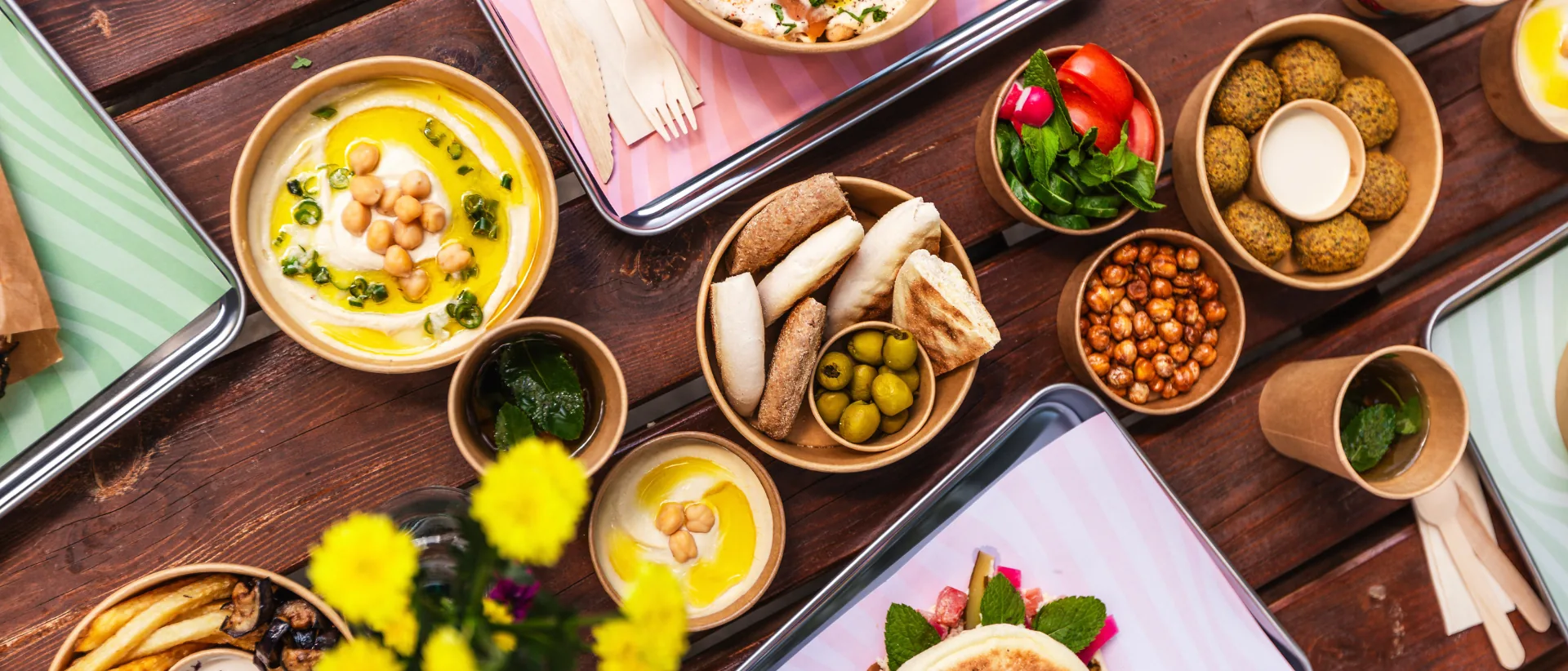 A long table laid with Nabäti catering trays, dips, falafel and fresh bread