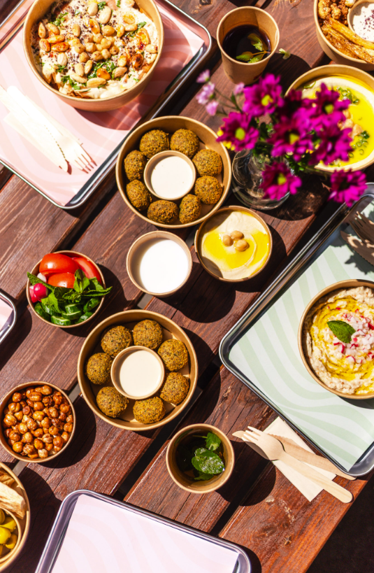 Catering spread of falafel, hummus and mezze bowls on a table at Nabäti Eatery Rotterdam