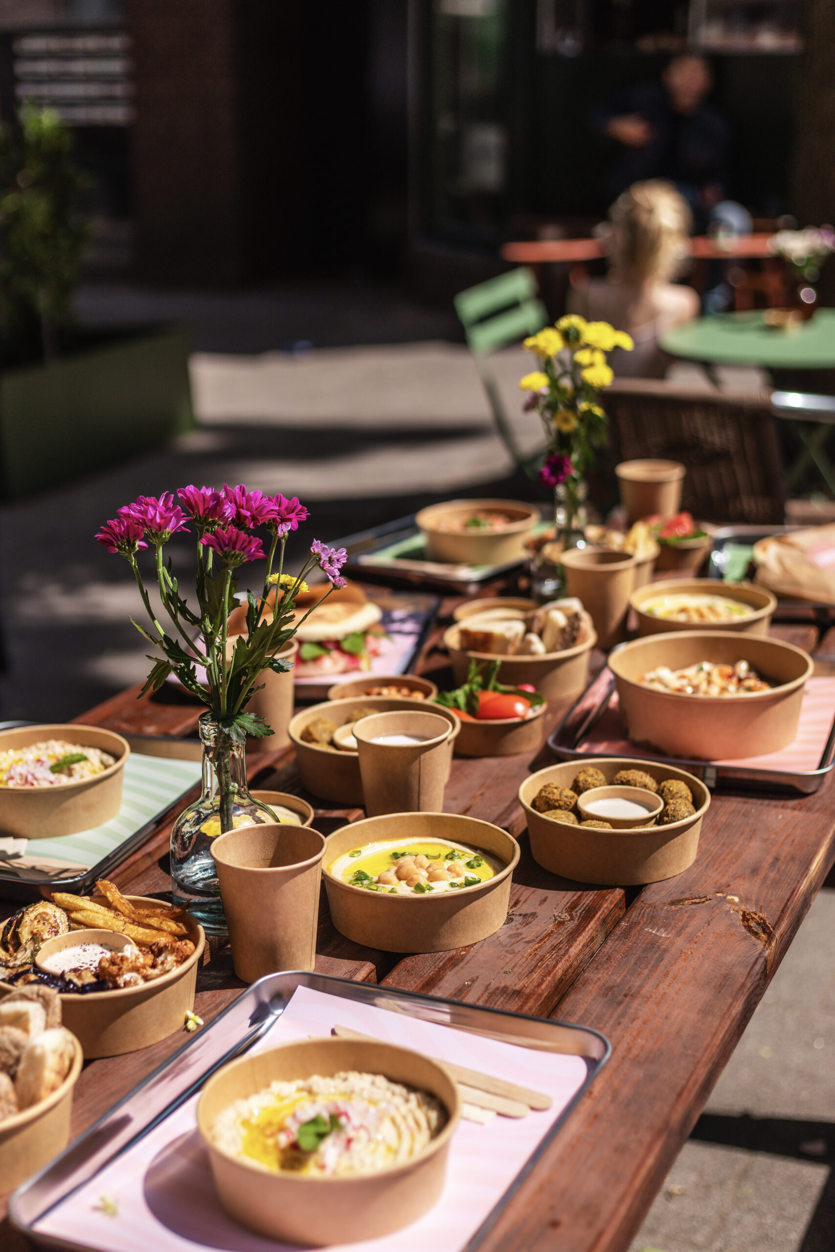 Gedekte buitentafel met mezzeschotels en bloemen bij Nabäti Eatery Rotterdam
