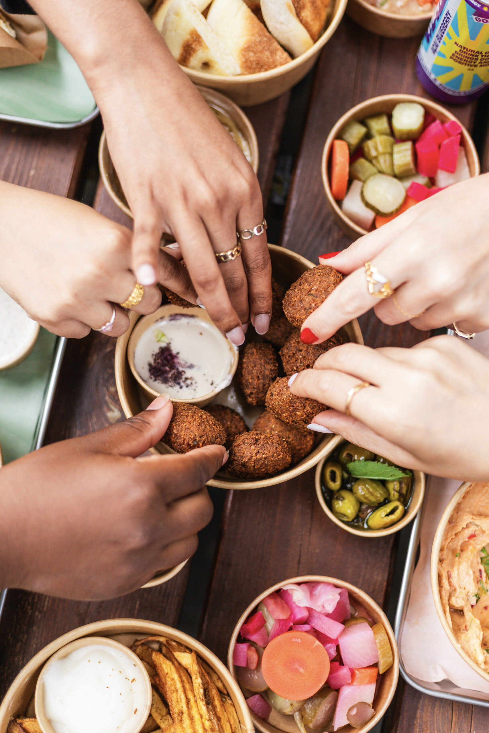 Handen delen falafel en mezze aan tafel bij Nabäti Eatery Rotterdam