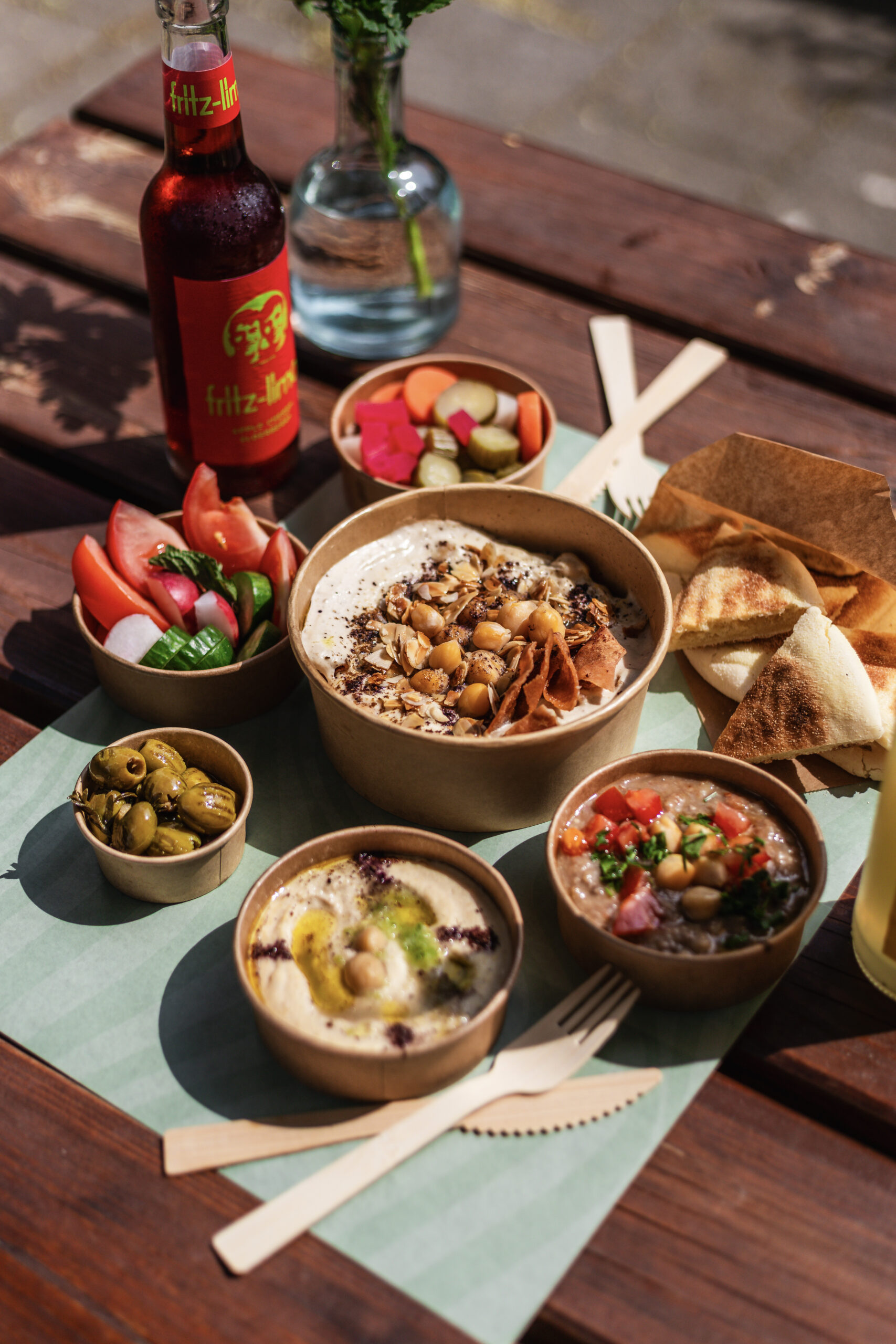 Tafel vol mezzeschotels, dips en pita met een drankje bij Nabäti Eatery Rotterdam